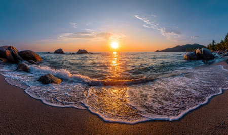 Panoramic beach sunset with golden sun over ocean, waves rolling onto sandy shoreの素材