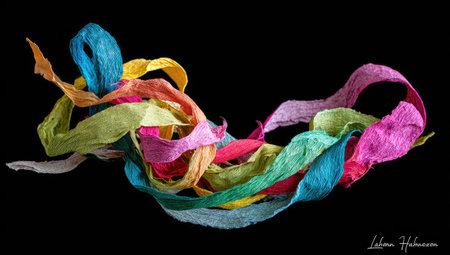 Various colorful ribbons, including blue, yellow, and pink, are shown against a stark black backdrop. The ribbons appear textured, possibly paper, and are arranged in a flowing, dynamic composition. The lighting is even, highlighting the colors. This image could be used for design elements or artistic projects.の素材