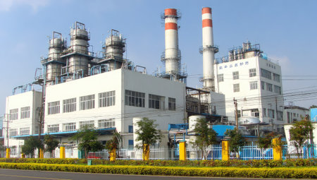 An industrial complex is shown with large buildings, chimneys, and associated infrastructure. The image displays a clear sky with bright daylight illuminating the scene. The composition could serve diverse commercial applications, including illustrating industry, energy, or engineering concepts. The image is suitable for various editorial and commercial projects.の素材