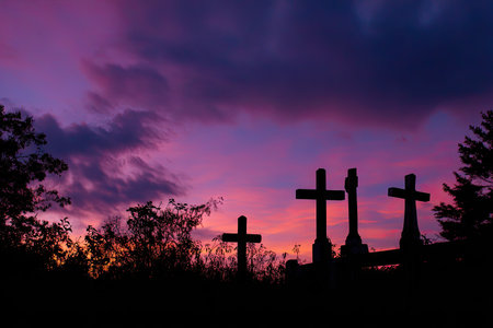 Dark silhouettes of crosses stand against a colorful sky. The image features an outdoor setting with vibrant shades of purple, orange, and deep blue dominating the background. The composition suggests a serene atmosphere, potentially suitable for editorial or commercial projects conveying themes of faith or reflection.の素材