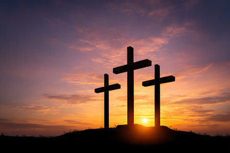 Three dark crosses stand silhouetted on a small hill, set against a vividly colored sky during sunset. The composition showcases bold contrasts between dark forms and bright colors. The image's lighting suggests an outdoor setting, possibly suitable for editorial or commercial applications seeking symbolic representations.の素材