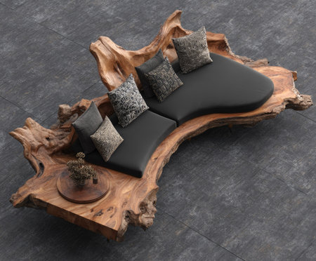 This image presents an artistic sofa construction featuring dark seating cushions. It includes several decorative pillows, and a side table arrangement, all set within a natural wood base. The composition showcases the objects against a dark background. It is suitable for use in marketing materials for interior design projects.の素材