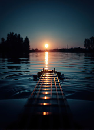 An acoustic guitar rests atop water, bathed in the warm glow of the setting sun. The image displays a close-up of the fretboard and strings, with the lake stretching toward the horizon. The scene evokes a serene mood with a dark blue atmosphere. This photograph is suitable for various visual projects.の素材