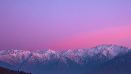 The image showcases mountain peaks covered with snow under a gradient sky with shades of purple and pink. The composition displays a wide shot, emphasizing the vastness of the landscape. The lighting suggests a sunset or sunrise scene, creating a serene and visually appealing setting. Suitable for a variety of editorial and commercial purposes.の素材