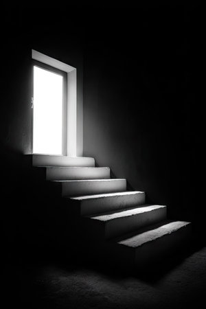 A staircase ascends towards an open doorway illuminating a dark interior. The composition features a strong contrast between light and shadow, highlighting architectural elements. The monochromatic palette emphasizes texture and form. Suitable for conceptual illustrations, potentially used in advertising or editorial projects, conveying themes of opportunity or transition.の素材