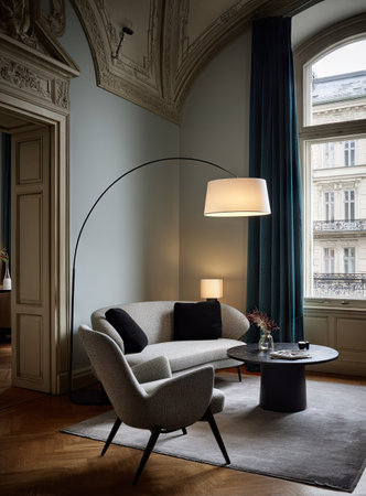 An indoor shot features a furnished living area with a curved lamp, a sofa, and chairs. The scene displays a modern aesthetic with neutral tones, dark accents, and natural light. It is suitable for use in design, interior, and lifestyle editorial and commercial applications.の素材