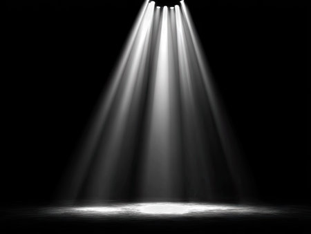 Several bright beams of light emanate from above, creating a dynamic visual effect against a deep black backdrop. The composition features strong overhead lighting, with the beams converging towards a central point. The image offers potential for use in visual design, advertising campaigns, or illustrative projects.の素材