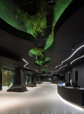 A contemporary interior showcases a unique architectural design. The scene features a dark color palette with striking lighting accents and textured walls. Green vegetation adds a natural element. This image could be used to illustrate concepts related to design, architecture, or interior spaces in promotional or editorial contexts.の素材