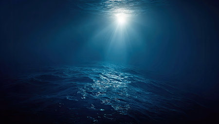 An abstract underwater scene showcases sunlight filtering through the water. The image features dark blue hues and subtle textures, suggesting a deep-sea environment. This visual could be utilized for various commercial purposes, providing a calming and mysterious backdrop.の素材