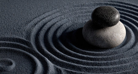 Two stones rest atop raked sand, forming a minimalist composition. The contrasting textures and colors of the dark stone on light stone create a visual point of interest. The image showcases a serene environment with curved patterns and soft shadows. This image is suitable for various design and editorial applications.の素材