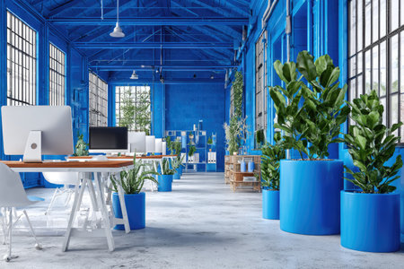 The image displays a spacious office interior, dominated by shades of blue. A computer and desk are centered, complemented by potted plants. The style suggests a modern design, likely in a building with large windows. The overall look hints at a workspace, ideal for corporate visuals and editorial projects.の素材