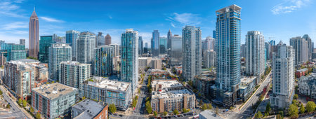An aerial view showcases a dense cityscape filled with tall buildings and towers. The image presents an array of modern architectural designs, featuring glass and metal facades. The sky is a brilliant blue, with good lighting. This imagery could be used for illustrating concepts related to urban development or infrastructure.の素材