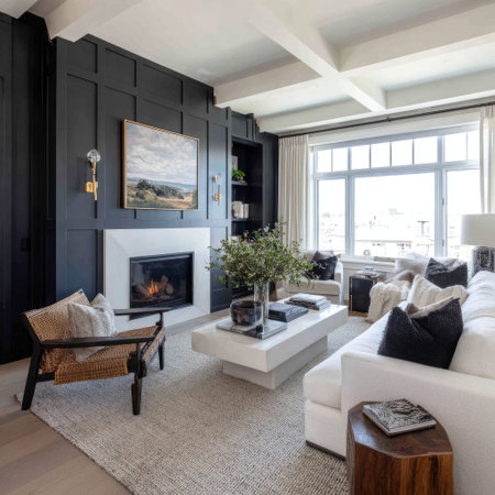 An interior shot presents a modern living room dominated by a dark feature wall with a fireplace. The space is furnished with white sofas, a low coffee table, and wooden accents. Daylight streams through large windows, illuminating the room and highlighting its textures. This image is suitable for architectural design, home decor, and lifestyle publications.の素材