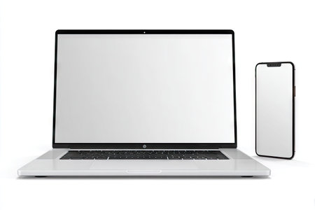A laptop and smartphone are presented with blank screens on a clean white backdrop. The objects exhibit a modern, minimalist design. The composition utilizes overhead lighting with a focus on the devices. This image can be applied in various digital advertising and marketing contexts.の素材