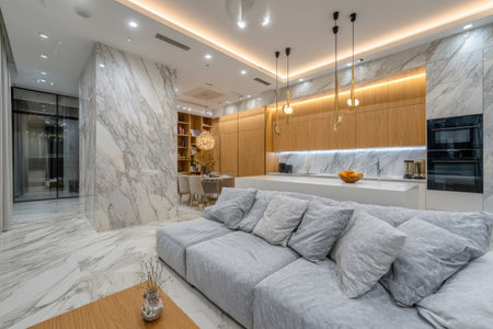 An interior view depicts a luxury living space with a kitchen area. The scene showcases a neutral color palette, including light gray, white, and wood. Lighting elements enhance the modern design. This image is suitable for illustrating concepts of interior design, architecture, or home decor.の素材