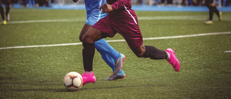 This image captures soccer players engaged in a dynamic game. The scene features a green field with white lines and players wearing dark and light blue uniforms. The players are actively kicking the ball. Suitable for sports, action, and competition themed visual content.の素材