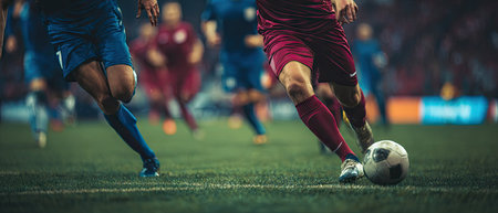The image depicts soccer players during a match, focused on the legs and ball. The composition showcases dynamic movement, emphasizing the sport's activity. The color scheme is dominated by green and blue, suggesting a stadium setting. This scene can be suitable for promotional material or editorial content related to sports.の素材