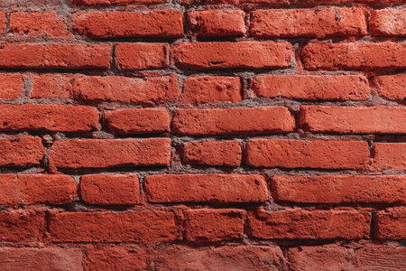 This image displays a close-up of a brick wall with a reddish-brown color palette. The texture of the bricks is rough and aged, with visible mortar between them. The lighting appears consistent across the surface, creating a sense of depth. The composition is suitable for various applications, including design and background use.の素材