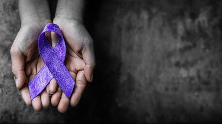 A close-up showcases hands gently holding a vibrant purple ribbon against a blurred backdrop. The image features a shallow depth of field, highlighting the textured ribbon. Composition is from an overhead perspective with soft, even lighting, suitable for various awareness campaigns and editorial projects.の素材