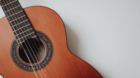 The image presents an acoustic guitar, featuring a warm wooden body and a detailed fretboard. Its strings are taut, and the instrument is positioned against a neutral white background. The composition utilizes natural lighting to highlight its texture and design. Suitable for diverse commercial applications, this image could serve various creative purposes.の素材