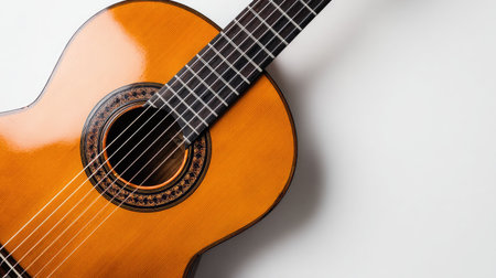 The image shows an acoustic guitar set against a white backdrop. The instrument has a glossy, warm-toned wood finish and a soundhole. The composition provides an overhead view, with the guitar positioned diagonally. This visual may be suitable for music-related editorials or product promotions.の素材