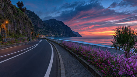 An asphalt road curves along a coast at dusk, with a sea and colorful sky. The composition features an overhead perspective. The image suggests a natural environment, with possible use in travel articles and commercial projects. The lighting and colors create an atmospheric aesthetic.の素材