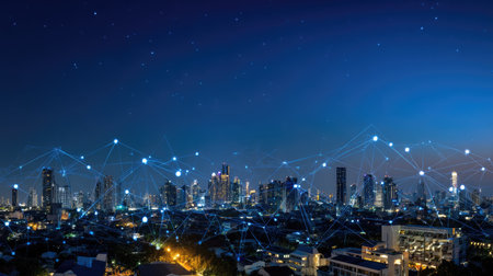 A nighttime cityscape is presented with bright lights against a deep blue sky. Illuminated skyscrapers and buildings form the urban environment. Digital connections are overlaid, depicting modern technology. This image could be utilized for business presentations or to represent technological advancements.の素材