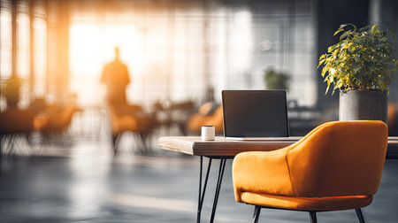 An office interior features a laptop on a desk, an orange chair, and a potted plant. The blurred figure of a person can be seen in the background. The scene utilizes warm sunlight and soft shadows. Suitable for business presentations, website backgrounds, or promotional materials.の素材