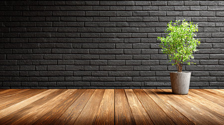 A vibrant green potted plant sits against a dark brick wall. The plant is illuminated by natural lighting from an unseen source. Wooden flooring creates a contrasting texture and warm tone in the lower portion of the frame. This image is appropriate for commercial use in various projects.の素材