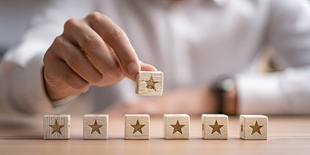 Businessman placing five wooden stars on a row of wooden cubes.の素材