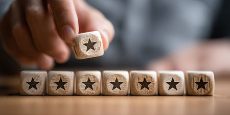 Conceptual image of star rating on wooden cubes with man's handの素材