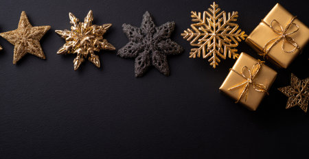 An overhead view displays a collection of golden stars, snowflake ornaments, and wrapped presents set against a dark, contrasting background. The composition uses symmetrical balance, with warm highlights emphasizing the textures. This image could be used for various projects, including holiday promotions or design elements.の素材