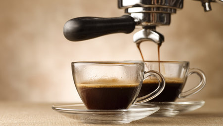 An espresso machine dispenses freshly brewed coffee into two transparent cups. The image showcases the dark liquid against a light background. The lighting is focused, highlighting the details of the machine and the cups. This could be used for advertisements related to coffee or beverages.の素材