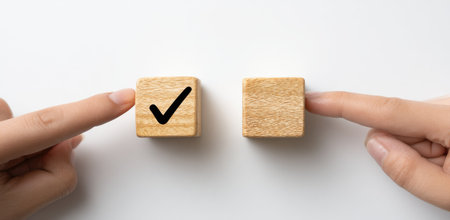 Two hands interact with wooden cubes against a white backdrop. One cube features a black check mark, the other is blank. The composition uses overhead lighting, creating a clean, minimalistic aesthetic. Suitable for various commercial uses, including website design and marketing materials, highlighting the idea of choice.の素材