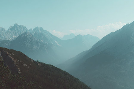 This image showcases a scenic mountain range under a clear sky. The composition reveals varying shades of blue and gray, creating a sense of depth and tranquility. The lighting suggests a daytime setting. Ideal for use in travel, nature, or environmental projects.の素材