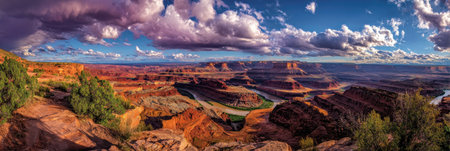 This panoramic image displays a vast canyon landscape under a dynamic sky filled with clouds. The scene showcases rock formations and geological features. Warm colors and textures dominate the composition, while the lighting creates depth. Suitable for various applications, including travel, nature, or environmental themes.の素材