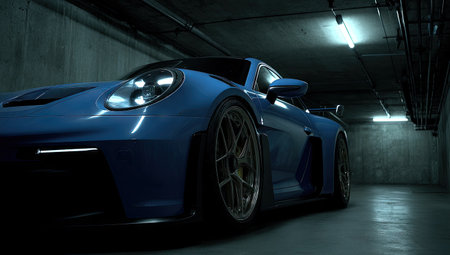A striking blue sports car is captured in a low-angle shot within a dark, industrial space. The car's lines are emphasized by the soft, diffused lighting. The image showcases the vehicle's design and engineering. Suitable for automotive content, marketing materials, and editorial projects.の素材