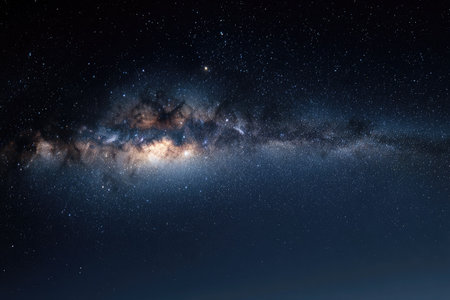 This image showcases the majestic Milky Way galaxy spanning across a dark night sky. The celestial display features vibrant colors, intricate textures, and a panoramic composition. The scene suggests an outdoor environment, possibly a remote area. This visual could be used for various commercial and editorial projects.の素材