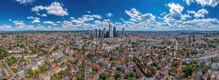 An aerial view presents a sprawling cityscape under a vibrant blue sky dotted with clouds. The scene encompasses a dense urban environment with numerous buildings and structures. The image could be used for illustrating urban development, business, or architecture. It provides a visual for diverse projects.の素材