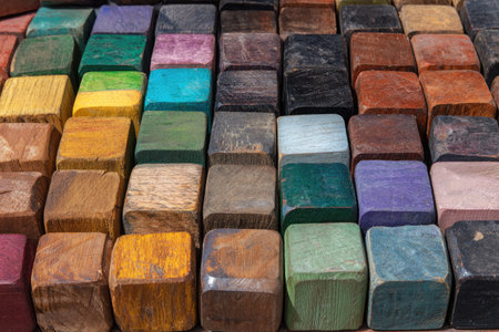 An overhead view displays many wooden cubes with varied colors. The composition reveals a grid formation, with each cube presenting different shades. Natural light enhances the texture, emphasizing the grain and surface details. This image could be useful for backgrounds or design elements.の素材