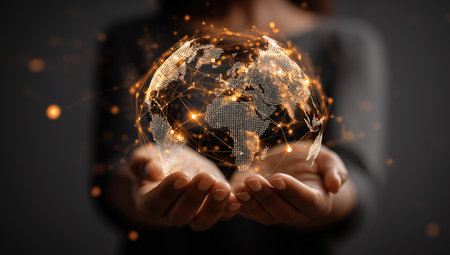 A person holds a glowing globe, its surface highlighted by a network of interconnected lines. Warm orange light emanates from the sphere, contrasting against a dark background. The composition suggests connectivity and technological advancement. Potential uses include illustrations for business, science, or conceptual designs.の素材