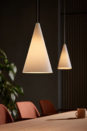 Two cone-shaped pendant lights hang over a dining table, illuminating the space with a soft, warm glow. The composition features a neutral color palette, highlighting the lights' design against a dark backdrop. This image may be suitable for interior design, home decor, or commercial projects.の素材