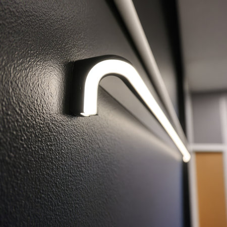 A close-up view displays a modern lighting fixture mounted on a textured black wall. The fixture emits bright white light, casting a glow against the dark surface. The composition suggests an interior setting with neutral tones. It could be suitable for various commercial design, decoration, or architectural concepts.の素材