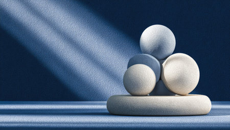 This image presents a minimalist arrangement of spheres atop a circular platform. The scene is illuminated by dramatic lighting, casting shadows on the dark blue backdrop. The smooth textures and clean lines create a modern aesthetic suitable for various applications, including advertising and editorial content.の素材