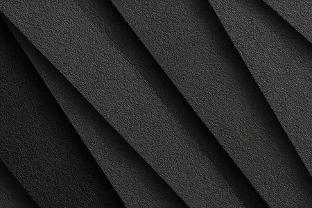 This image presents an abstract composition of dark gray textured paper, arranged in diagonal folds. The interplay of light and shadow highlights the paper's texture, creating a pattern. The design appears suitable for various uses, including graphic design, website backgrounds, or print materials. The image evokes a sense of depth and form.の素材