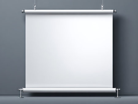 A rectangular projection screen hangs suspended against a smooth, gray wall. The clean white surface of the screen provides a stark contrast. The composition is simple, suggesting a studio setting. This image could be used for presentations, advertising, or as a background template. Suitable for various commercial and editorial projects.の素材