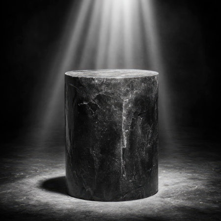 A dark, cylindrical stone pedestal is centrally positioned, dramatically lit by overhead beams of light. The image displays a high-contrast style, showing textured stone against a shadowed background. This presentation is ideal for showcasing products, offering a visually captivating scene suitable for advertising and design projects.の素材