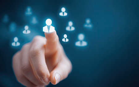 A human hand touches a glowing user icon, suggesting selection or interaction. The image presents a dark blue backdrop with multiple illuminated user symbols. The composition includes a close-up focus on the finger and icons. Suitable for visual elements in concept of internet or user interface design.の素材