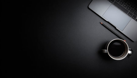 An overhead view reveals a workspace featuring a laptop, coffee cup, and pencil arranged on a dark, flat surface. The composition showcases a minimalist style with a focus on dark tones and subtle textures. Ideal for illustrating work-related concepts, this image is suitable for a variety of commercial applications.の素材