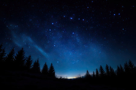 A nighttime landscape presents a dark forest silhouetted against a brilliant sky. The deep blue gradient showcases numerous stars and faint celestial formations. Overhead illumination suggests a distant source. Suitable for illustrating astronomical concepts or evoking a sense of wonder in a natural environment, this image may serve commercial applications.の素材